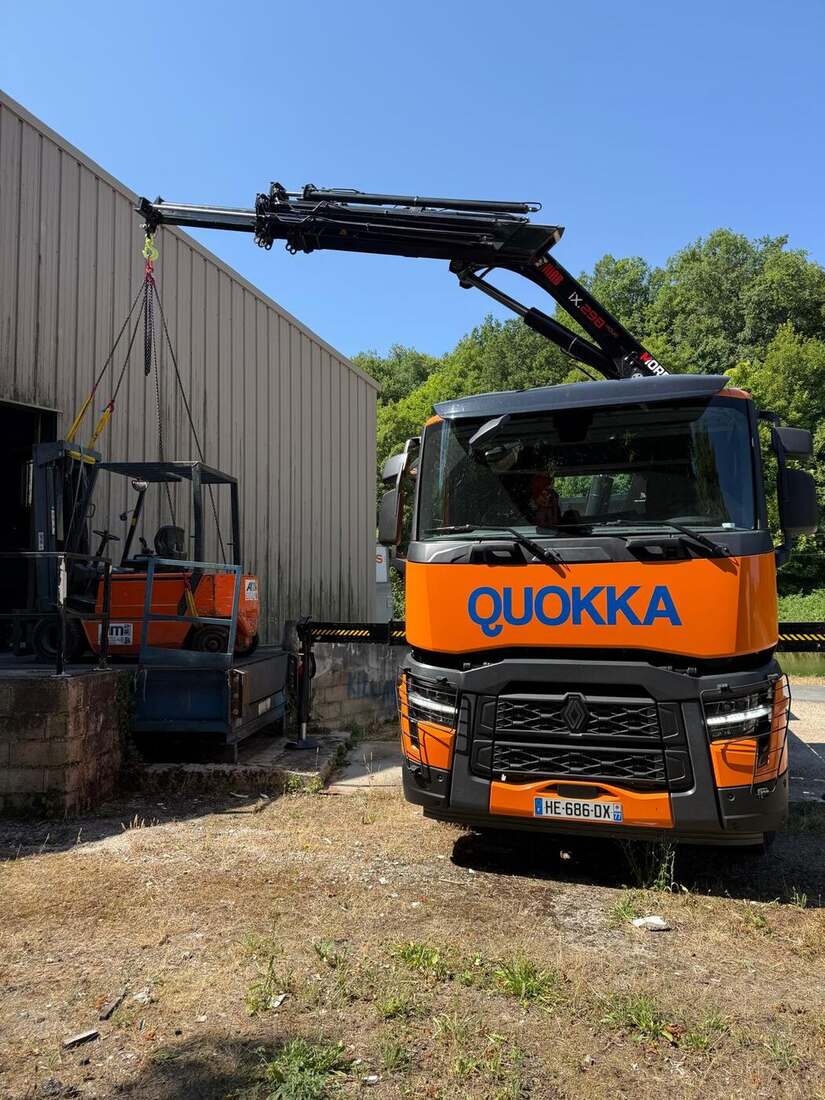 Camion-grue Quokka levant une nacelle devant un entrepôt